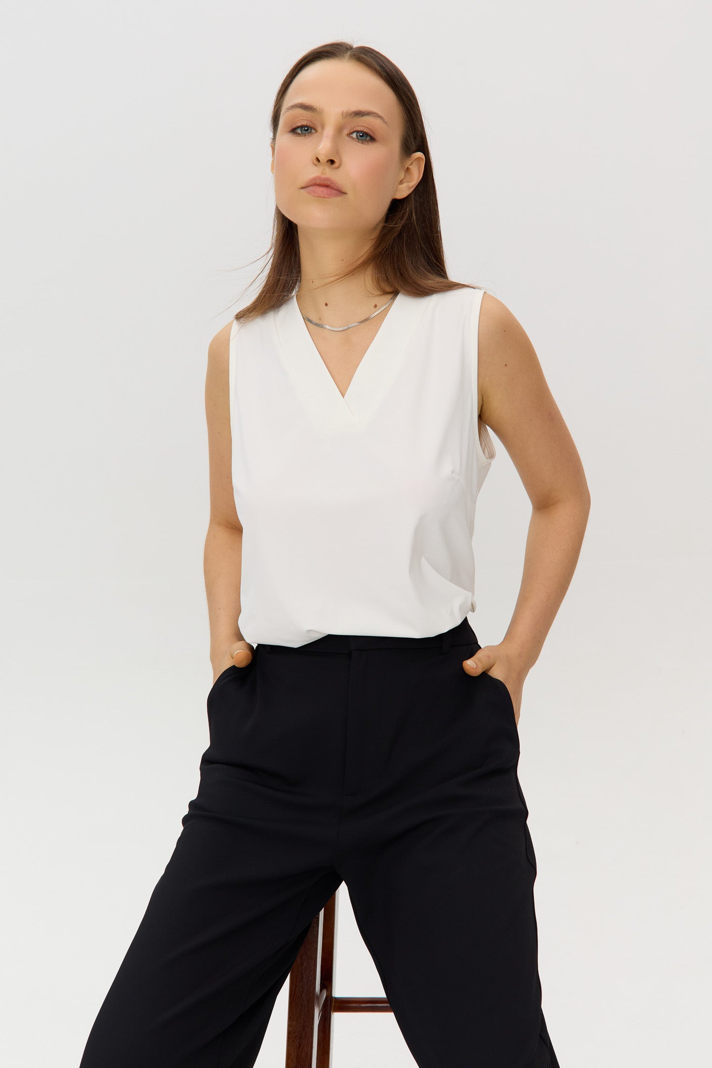 White Sleeveless V-neck halter top in a soft, stretchy fabric, worn by a model.